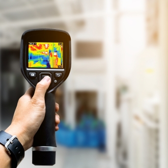 technician use thermal imaging camera to check temperature in factory